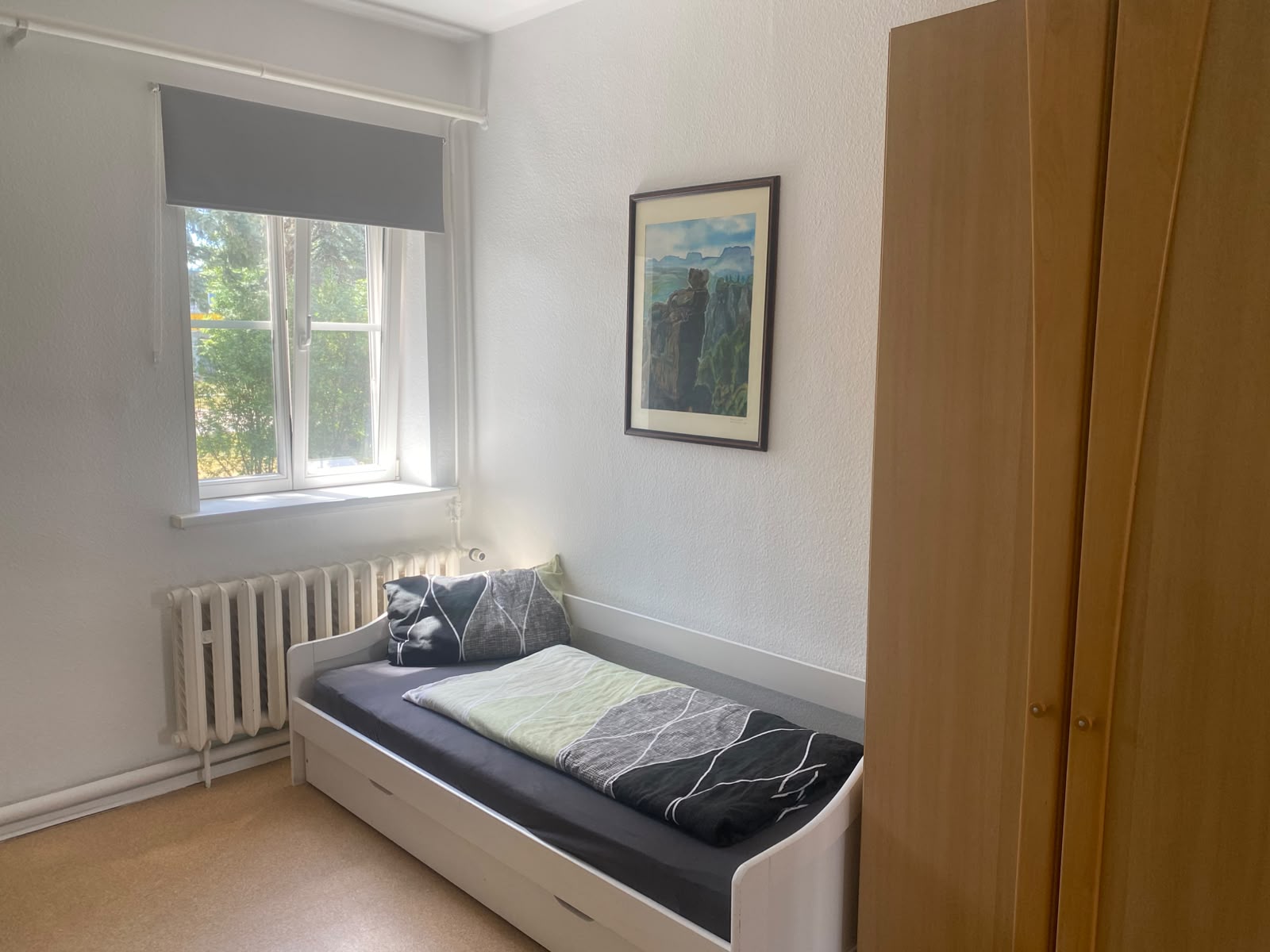 Einzelzimmer mit frisch gestrichenen Wänden und Bett am Fenster